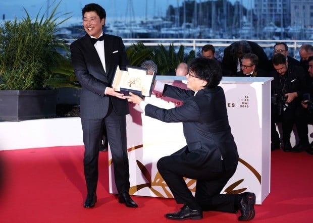 프랑스 칸영화제 '황금종려상'을 수상한 봉준호 감독(오른쪽)이 영화 '기생충'의 주연배우이자, 자신의 페르소나(persona)인 송강호에게 무릎을 꿇고 상패를 건네고 있다. 사진=연합뉴스