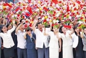 평양 시민들이 시진핑 주석과 김정은이 함께 탄 무개차를 향해 꽃다발을 흔들고 있다.  /연합뉴스  