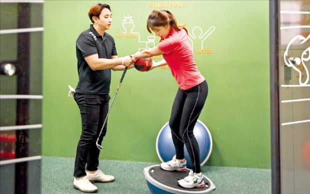 28일 서울 서초구에 있는 골프 아카데미 ‘이룸골프’를 찾은 한 회원이 골프 전문 트레이너로부터 ‘골프 피트니스’를 배우고 있다. 반구형 기구는 균형잡기 훈련에 쓰이는 ‘돔볼’이다.  /이룸골프 제공 