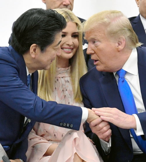 아베 신조(安倍晋三) 일본 총리(왼쪽)과 도널드 트럼프 미국 대통령(오른쪽)이 29일 일본 오사카에서 열린 주요 20개국(G20) 정상회의의 특별 세션에서 트럼프 대통령의 딸 이방카를 사이에 두고 서로 손을 잡으며 대화를 나누고 있다. 사진=연합뉴스