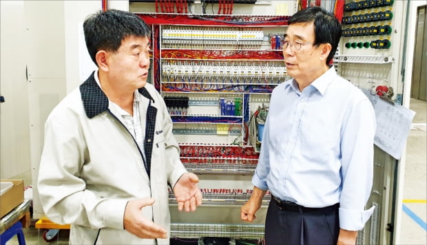 서호전기의 이상호 회장(오른쪽)과 김승남 사장이 안양 공장 내 항만 자동화 크레인 컨트롤러 앞에서 영상인식 기술 개발과 관련해 의견을 나누고 있다.  