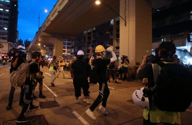 지난 17일 오후(현지시간) 방독면과 안전모를 쓴 시위대가 홍콩 카오룽반도 몽콕경찰서를 지키고 있는 경찰을 향해 돌을 던지고 있다. (사진=연합뉴스)