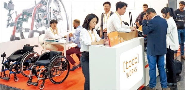 독일 뒤셀도르프에서 최근 열린 ‘국제재활·실버제품전시회(REHACARE·레하케어)’에서 참관객들이 국내 의료기기업체인 토도웍스 부스에서 상담하고 있다. 이 회사는 수동휠체어를 전동휠체어로 바꿔주는 키트를 출품했다.  /임유  기자 