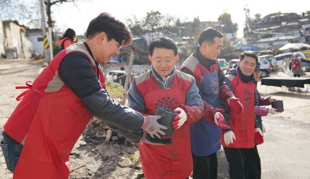 롯데건설 하석주 대표이사(왼쪽에서 두 번째)가 샤롯데 봉사단원들과 함께 연탄을 나르고 있다.