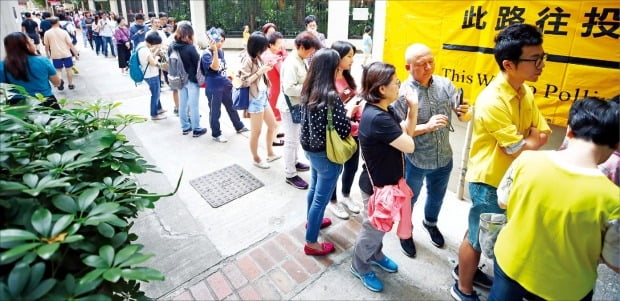 홍콩 구의원 선거일인 24일 코즈웨이베이 커뮤니티센터에 설치된 투표소에서 시민들이 투표하기 위해 줄지어 서 있다. 홍콩 시민들은 이날 선거를 통해 18개 선거구에서 구의원 452명을 선출한다.   /연합뉴스 