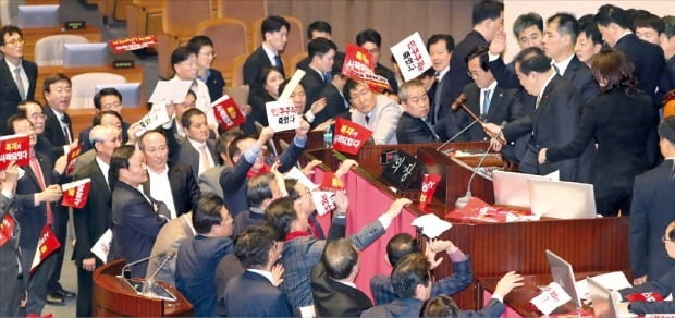 < 격렬 항의 > 문희상 국회의장이 27일 열린 국회 본회의에서 공직선거법에 대한 투표 절차를 진행하는 의사봉을 두드리자 의장석을 에워싼 자유한국당 의원들이 ‘독재가 시작됐다’고 적힌 푯말을 던지고 “문희상 사퇴” 구호를 외치면서 격하게 항의하고 있다.  연합뉴스 