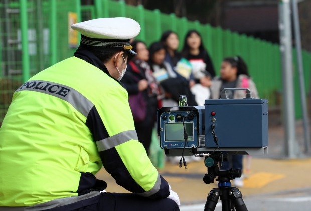 대전 둔산경찰서 관계자가 11일 오후 서구 둔산동 한 초등학교 앞 어린이보호구역(스쿨존)에서 과속 차량을 단속하고 있다. 국회는 스쿨존에 과속단속 카메라 설치를 의무화하고, 스쿨존 내 사망사고 가해자를 가중처벌하는 것을 골자로 하는 '민식이법'을 상정·처리했다. (사진=연합뉴스)