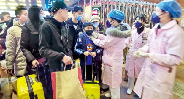 중국 정부는 23일 ‘우한 폐렴’의 발원지인 우한시를 일시 봉쇄하는 긴급 조치를 내렸다. 우한에서 남동쪽으로 510여㎞ 떨어진 잉탄시의 기차역에서 검역원들이 승객의 체온을 재고 있다. AFP연합뉴스