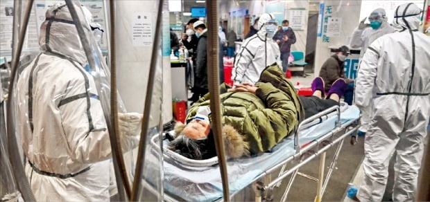 방역복을 입은 의료진이 지난 25일 중국 우한 적십자병원에서 신종 코로나바이러스(우한 폐렴) 감염 환자를 이송하고 있다. /AFP연합뉴스 