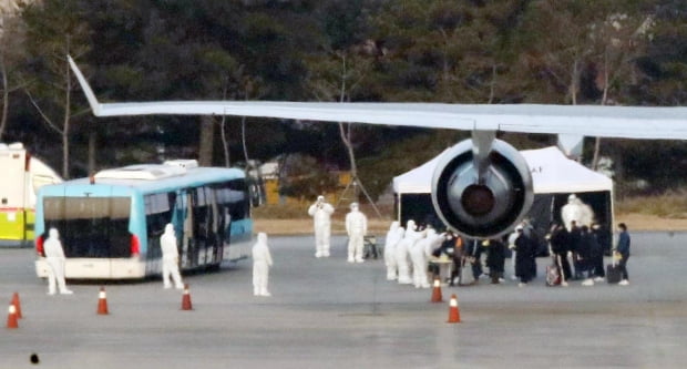 전세기를 타고 김포국제공항에 도착한 교민들이 버스에 탑승하기 전 방역을 받고 있다. 사진=연합뉴스