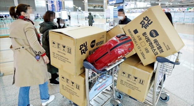 3일 인천국제공항 제1터미널에서 중국인 여행객들이 보건용 마스크가 담긴 카트를 세워둔 채 탑승수속 절차를 밟고 있다.  /연합뉴스 