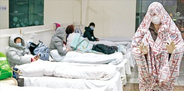 중국 우한시 정부는 늘어나는 우한 폐렴 환자를 수용하기 위해 컨벤션센터 등을 임시병원으로 개조해 사용하고 있다. 지난 5일 우한의 한 임시병원에서 침대 시트를 뒤집어쓴 환자가 병원을 다니고 있다. AFP연합뉴스 
