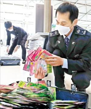 인천세관 직원들이 6일 인천국제공항 출국장에서 외국인의 가방을 열어 반출하는 마스크 수를 세어 보고 있다.  연합뉴스 