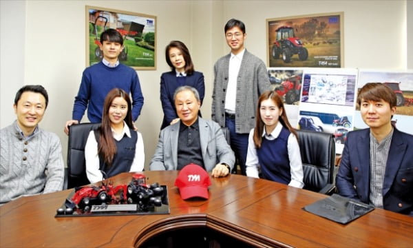 유가증권시장 중소형주 동양물산의 김희용 회장(앞줄 가운데) 등 임직원들이 서울 논현동 본사에서 회사의 제품인 농기계 모형을 앞에 두고 환하게 웃고 있다.  동양물산 제공 