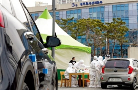 정부가 13일 정부세종청사 인근에 긴급 설치한 ‘드라이브 스루’ 선별진료소에서 의료진이 자동차를 타고 온 시민을 대상으로 코로나19 진단 검사를 하고 있다.  /연합뉴스 