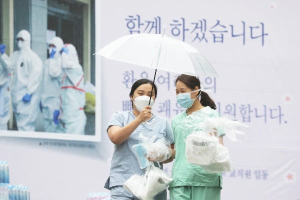 10일 오전 대구시 신종 코로나바이러스 감염증(코로나19) 지역거점병원인 계명대학교 대구동산병원에서 간호사들이 우산을 쓰고 보호구 착의실로 향하고 있다/사진=연합뉴스