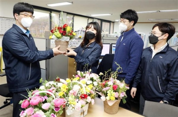 한국지역난방공사는 코로나19로 어려움을 겪는 지역 화훼농가를 지원하기 위해 1000만원 꽃 구매행사를 열었다. 지역난방공사 직원들이 사무실에서 꽃바구니를 나눠 갖고 있다.  지역난방공사 제공
 