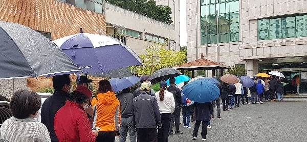 11일 오후 울산시 남구 옥동 울산보훈지청 사전투표소에서 줄을 길게 늘어선 유권자들이 갑작스럽게 비가 내리자 우산을 꺼내 쓰거나 그대로 비를 맞으면서 투표 순서를 기다리고 있다. 사진=연합뉴스