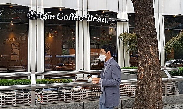 20일 서울 광화문역 인근 커피빈 매장에서 커피를 구입한 고객이 매장을 지나치고 있다. (사진=오정민 한경닷컴 기자)