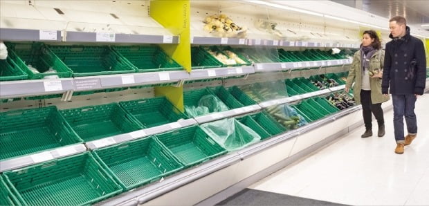 코로나19 확산에 따른 사재기로 지난 3월 영국 런던에 있는 한 대형 식료품점의 텅 빈 매대를 쇼핑객들이 살펴보고 있다. /한경DB 