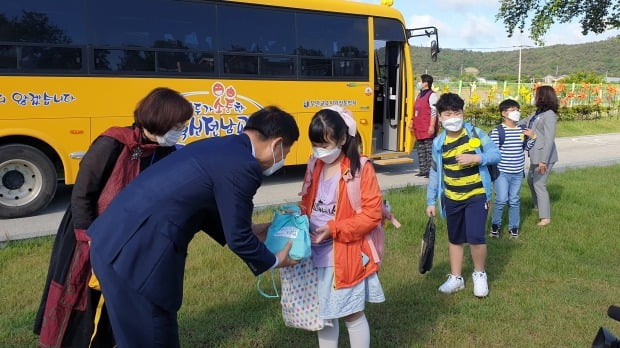 신종 코로나바이러스 감염증(코로나19)으로 올해 첫 등교를 시작한 20일 오전 전남 무안군 일로동초등학교에서 통학버스를 타고 등교한 학생들이 교실로 들어가기 전 방역 물품이 담긴 꾸러미를 건네받고 있다. 이날부터 고등학교 3학년이 개학했고, 60명 이하 소규모 초·중학교도 교장 재량으로 등교를 시작했다./ 사진=연합뉴스