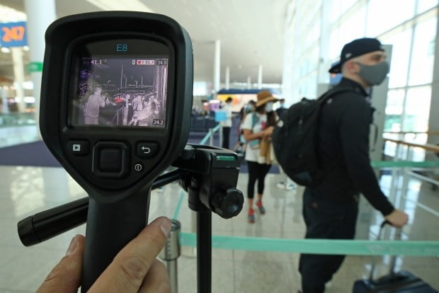 인천국제공항에서 관계자가 마스크를 쓴 승객들의 체온을 측정하고 있다. /사진=연합뉴스