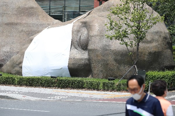 지난 17일 대구 달서구 진천동 선사유적공원 진입로에 옆으로 누워 잠자는 원시인 형상의 조형물에 가로 3.5ｍ, 세로 3.7ｍ 크기의 초대형 마스크가 씌워져 시민들의 눈길을 끌고 있다. 대구 달서구청은 원시인 조형물에 마스크를 씌우는 퍼포먼스를 통해 '아직은 마스크를 벗을 때가 아니다'라는 메시지를 전달하고, 신종 코로나바이러스 감염증(코로나19) 극복을 위해 시민들의 마스크 쓰기 동참을 호소하기 위해 홍보 캠페인을 마련했다/사진=뉴스1