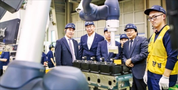 두산인프라코어와 한국로봇산업진흥원 관계자들이 협동로봇 설치 안전인증 1호를 획득한 G2엔진 생산공정을 살펴보고 있다.  두산 제공 