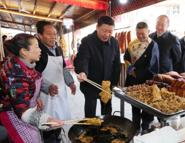 2018년 시진핑 중국 국가주석이 쓰촨성 잉씨우쩐의 한 마을에서 주민들을 만나 고기 튀김을 살펴보고 있다. 사진=중국 중앙방송국
