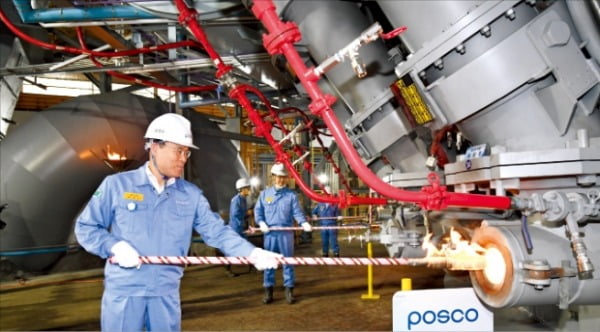 최정우 포스코 회장이 지난달 10일 전남 광양제철소에서 점화봉에 불을 붙인 뒤 3고로 풍구에 화입하고 있다.  포스코 제공 