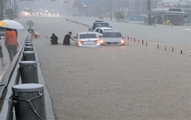 충남 천안에서 폭우로 도로가 침수된 가운데 시민들이 급하게 빠져나오고 있다.  /연합뉴스