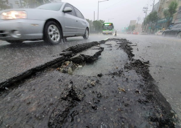 도로의 아스팔트가 밤새 내린 폭우에 뜯겨 나갔다. 사진=연합뉴스