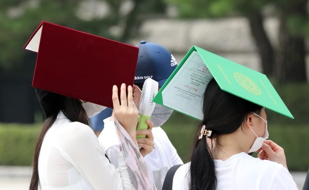 20일인 오늘도 전국 대부분 지역에서 무더위가 이어지겠다. 사진은 19일 경기도 용인시 경희대학교 국제캠퍼스에서 졸업생들이 더위를 피하기 위해 학위증을 머리에 올린 채 대기하고 있는 모습. 사진=뉴스1