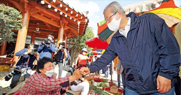 김종인 국민의힘 비상대책위원장이 지난달 폭우로 침수 피해를 본 전남 구례의 한 전통시장을 28일 방문해 상인들과 주먹인사를 하고 있다.  뉴스1 