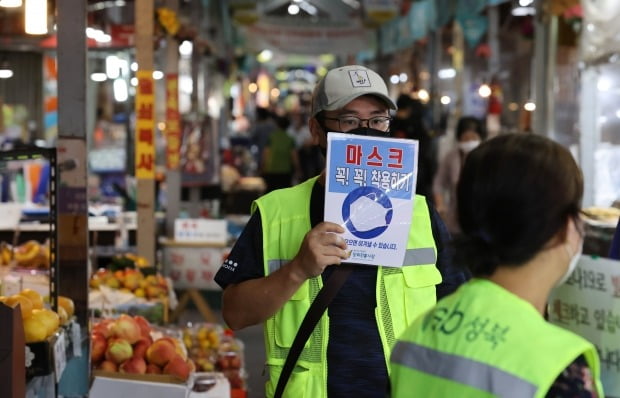 2일 오후 서울 성북구 사랑제일교회 인근 장위전통시장 입구에서 성북구청 관계자가 마스크 착용 팻말을 들어보이고 있다./ 사진=연합뉴스