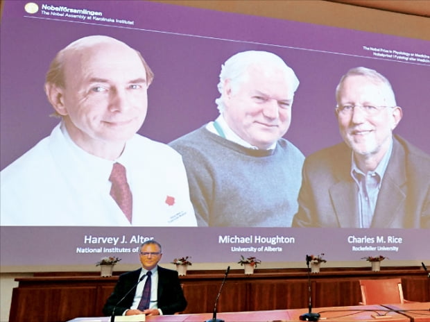 노벨위원회가 5일 노벨생리의학상 수상자를 발표하고 있다. 뒤쪽 스크린 왼쪽부터 하비 올터 미국 국립보건원(NIH) 교수와 마이클 호턴 캐나다 앨버타대 교수, 찰스 라이스 미국 록펠러대 교수.  AFP연합뉴스
