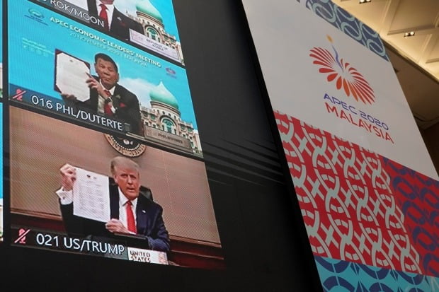도널드 트럼프 미국 대통령이 20일 열린 아시아태평양경제협력체(APEC) 화상 정상회의에서 다른 참가국 지도자들과 함께 '정상선언문'을 들고 있는 모습이 화면에 비치고 있다. 사진=AP