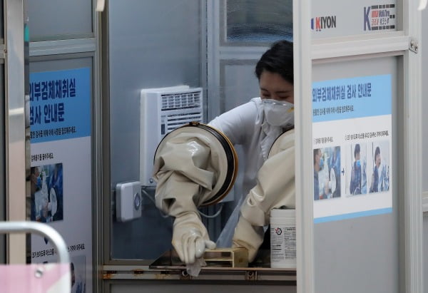 정부가 오는 19일부터 수도권의 사회적 거리두기 단계를 1단계에서 1.5단계로 격상하기로 한 지난 17일 오전 서울 중구 국립중앙의료원에 마련된 선별진료소에서 검체검사를 마친 의료진이 부스를 소독하고 있다/사진=뉴스1