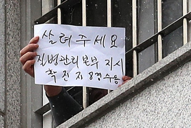 대규모 집단감염이 발생한 서울 동부구치소에서 한 수용자가 자필로 '살려주세요'라고 쓴 문구를 취재진에게 보여주고 있다.사진=뉴스1