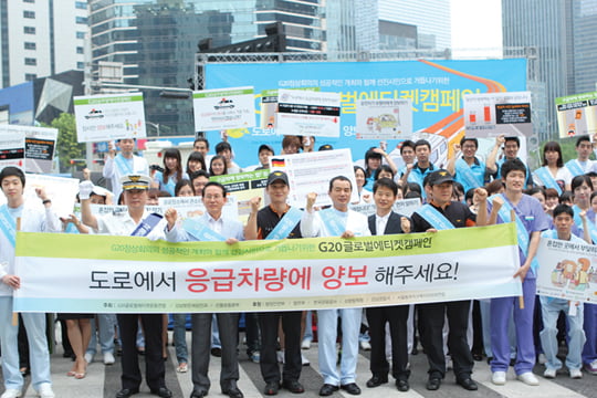 김 원장은 강남역에서 안과 직원들과 함께 글로벌 에티켓 캠페인의 일환으로 앰뷸런스에 길을 양보하자는 내용의 거리 캠페인을 벌이고 있다.