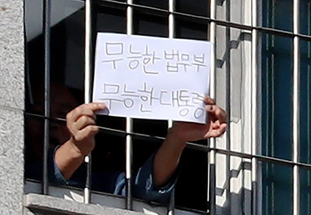 6일 오후 서울 송파구 동부구치소에서 한 수용자가 '무능한 법무부 무능한 대통령'이라고 쓴 종이를 창문 밖 취재진에게 내보이고 있다. 사진=연합뉴스