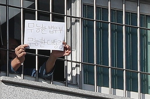 서울 송파구 동부구치소에서 한 재소자가 '무능한 법무부, 무능한 대통령'이라는 문구가 적힌 종이를 창살 너머로 꺼내 보이고 있다. 사진=뉴스1