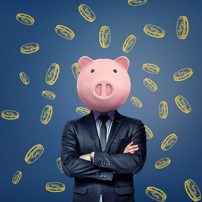 A businessman with folded arms stands wearing a pink pig mask on a background with chalk golden coins. Business and banking. Thinking to get rich. Money saving and investing.