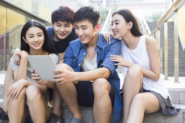 Young Chinese friends looking at digital tablet