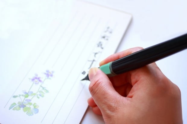 筆ペンで日本語のお手紙を書くシーン