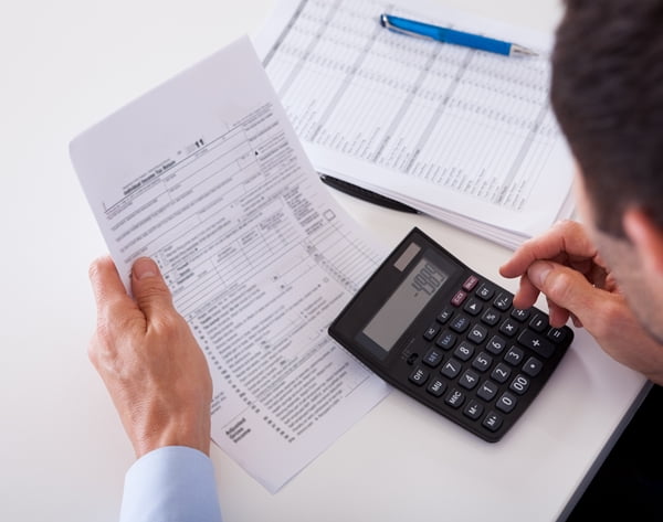 Over the shoulder view of a man checking an invoice on a calculator