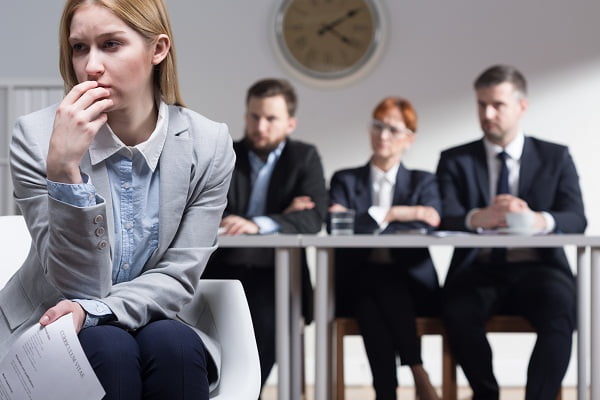 Sad woman holding CV and three businesspeople sitting beside table