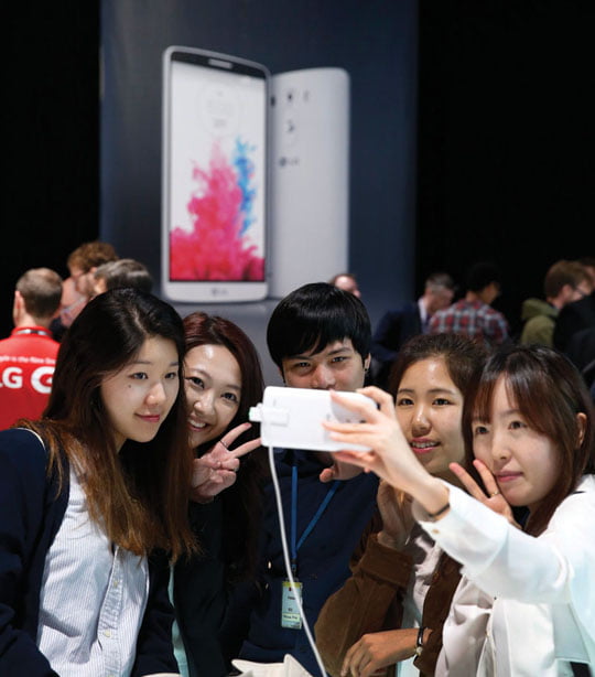 People pose for a selfie using LG's newly unveiled smartphone called the G3 at a press event in London, Tuesday, May 27, 2014. (AP Photo/Lefteris Pitarakis)