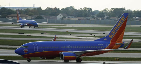 epa02361006 A Southwest Airlines jet taxis to takeoff as another one lands at Midway International Airport in Chicago, Illinois, USA 27 September 2010. Southwest Airlines and AirTran Airways both issued statements stating that Southwest Airlines has entered into a definitive agreement to acquire AirTran Holdings, Inc., a parent company of AirTran Airways (AirTran). The 1.4 billion US dollar deal is subject to regulatory and shareholder approval.  EPA/TANNEN MAURY