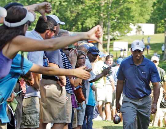 FILE - This April 30, 2010, file photo shows a woman, left, giving a thumbs down as Tiger Woods walks from the 15th hole during the second round of the Quail Hollow Championship golf tournament at Quail Hollow Club in Charlotte, N.C. Woods hasn't won in the year since he came back from his sex scandal, and some of his outings have been downright embarrassing. Woods claims his swing is the issue, but the real problem may be deeper than that.  (AP Photo/Chuck Burton, File)